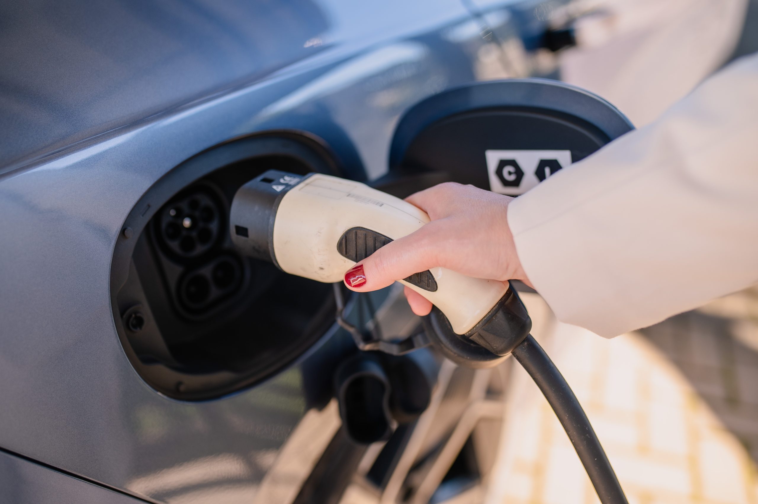 Pessoa realizando o carregamento de carro elétrico em estação de recarga, ilustrando como carregar carro elétrico de forma prática e eficiente.